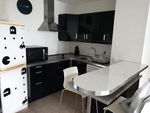 une cuisine avec des armoires noires et un comptoir blanc dans l'établissement Spacieux logement Prado Rabateau idéal Famille, à Marseille