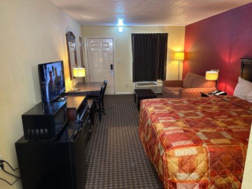 a hotel room with a bed and a desk at Royal Inn - Anniston in Anniston