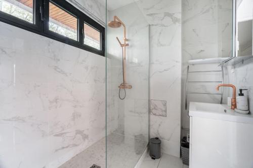 une salle de bain blanche avec une douche et un lavabo dans l'établissement A Refined 2-bedroom close Avenue Foch, à Paris
