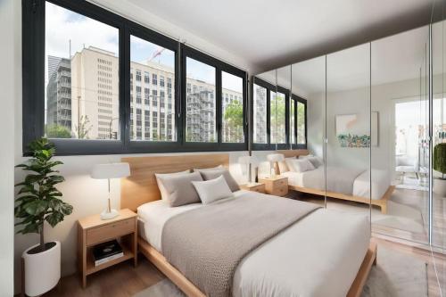 une chambre avec un grand lit blanc et de grandes fenêtres dans l'établissement A Refined 2-bedroom close Avenue Foch, à Paris