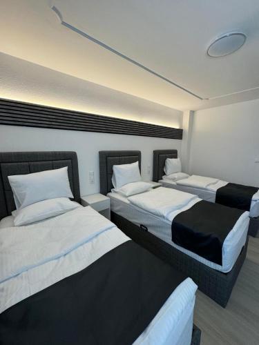a room with three beds with white sheets at DiDo Diamond Hotel in Dietzenbach