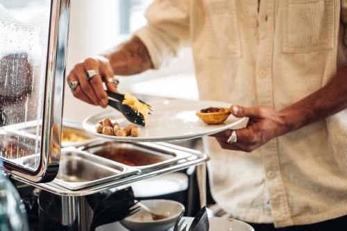 a chef holding a plate with food on it at Stay Hotel Lisboa Aeroporto in Lisbon