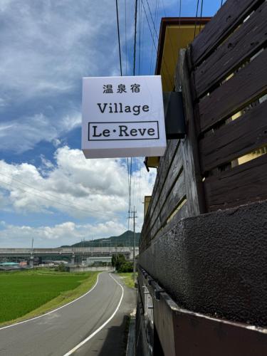 a sign that reads village le reyne on the side of a road at Village lereve in Takeo