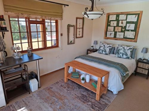 a bedroom with a bed and a desk and windows at Meadow View Guest Room in Wakkerstroom