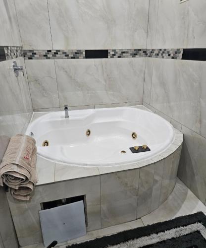 a white bath tub in a bathroom with marble walls at The Royal Princess B&B on Malibongwe Drive in Johannesburg