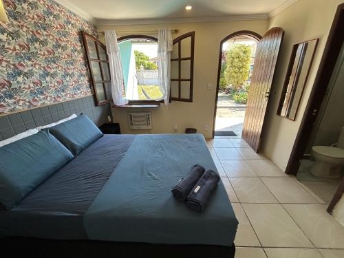 a bedroom with a large bed with blue sheets and a window at Pousada Brisa da Praia in Arraial do Cabo