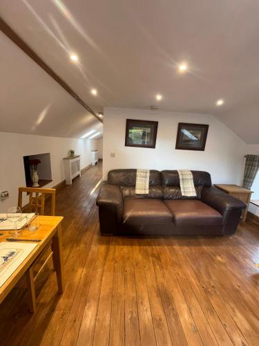 a living room with a leather couch and a table at Stewards Granary in Cornhill-on-tweed