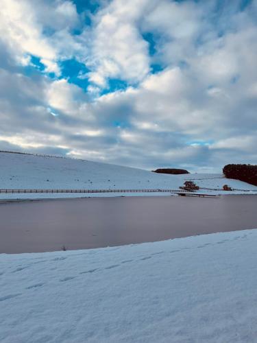a snow covered field with a bridge in the distance at Stewards Granary in Cornhill-on-tweed