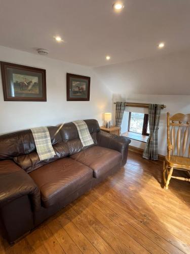 a brown leather couch in a living room at Stewards Granary in Cornhill-on-tweed