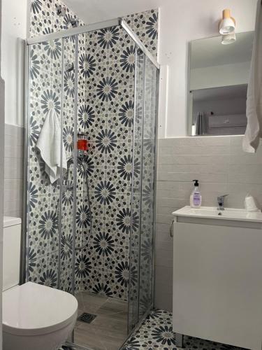 a bathroom with a shower with a toilet and a sink at Hostal Los Arcos in Vejer de la Frontera