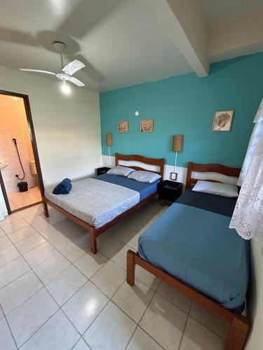 a bedroom with two beds and a blue wall at Pousada Brisa da Praia in Arraial do Cabo