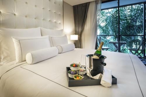 a hotel room with a bed with a bottle of champagne and drinks at Tastoria Collection Sukhumvit in Bangkok
