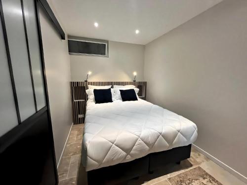 une chambre avec un grand lit blanc avec des oreillers noirs dans l'établissement Les Studios Famandiers, à Saint-Raphaël