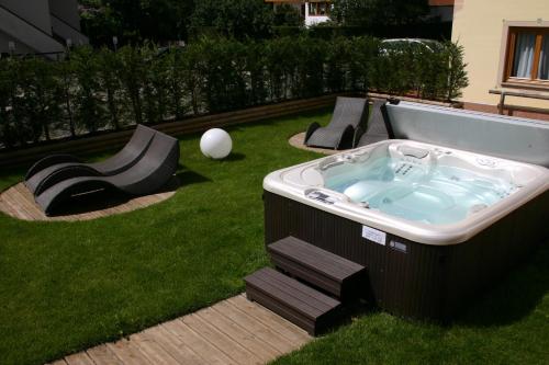 a hot tub in the grass with two benches at Residence Kristall- Fiemme Holidays in Predazzo