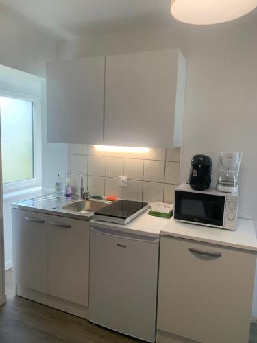 - une cuisine blanche avec un four micro-ondes et un évier dans l'établissement Charme St Malo, à Saint-Malo