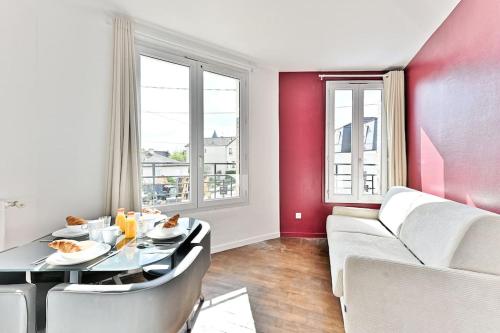 un salon avec une table et un canapé dans l'établissement Appartement Rose Moderne Proche de la capitale II, à Gagny