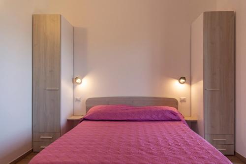 a bedroom with a bed with a pink blanket at Serra Cozy Apartments in Centola