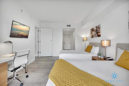 Una habitación de hotel con dos camas y un escritorio. en Infinite View Balcony Pool Near Beach, en Hallandale Beach