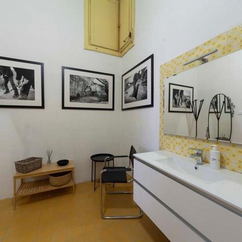 a bathroom with a sink and a table and pictures on the wall at B&B del Corso in Ascoli Piceno