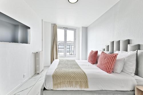 - une chambre blanche avec un grand lit et des oreillers rouges dans l'établissement Appartement Spacieux en banlieue parisienne - II, à Gagny