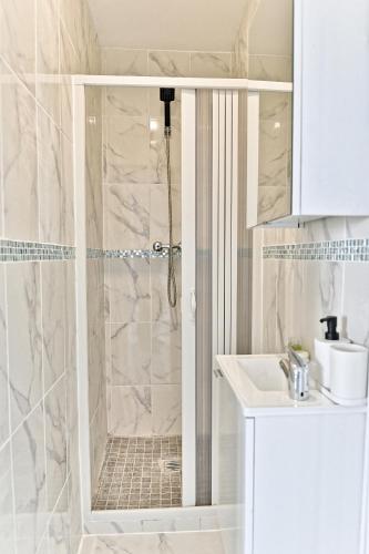 une salle de bain blanche avec une douche et un lavabo dans l'établissement Appartement Spacieux en banlieue parisienne - II, à Gagny