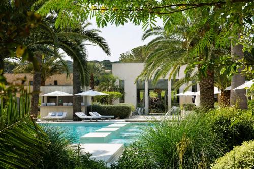 uma piscina com palmeiras e uma casa em Sezz Saint-Tropez em Saint-Tropez