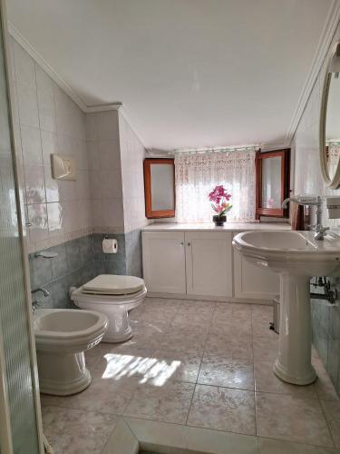 a bathroom with two sinks and a toilet and a window at Apposentu Sant'Antioco in SantʼAntìoco