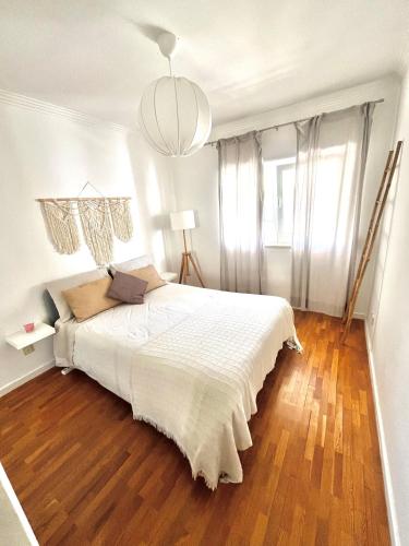 a bedroom with a white bed with a wooden floor at Mike Beach House in Costa da Caparica