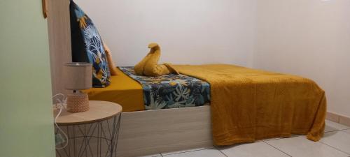 a bedroom with a bed with a yellow blanket and a chair at La kase de la cascade in Saint-Joseph