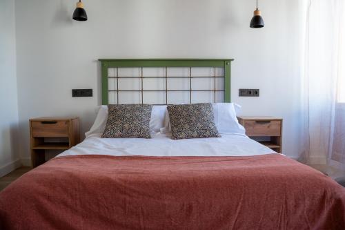 un letto con una coperta rossa e due cuscini sopra di Apartamentos Gomérez 30 a Granada
