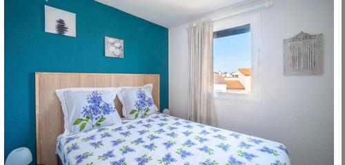 une chambre avec un lit aux murs bleus et une fenêtre dans l'établissement Appartement T2 bord de mer, à Saint-Cyprien