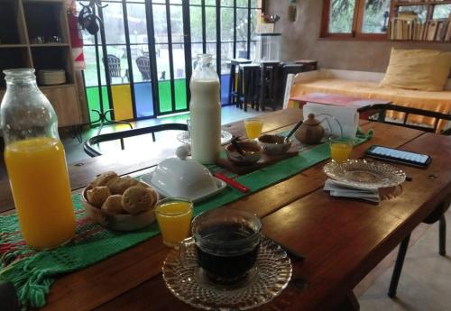 een houten tafel met een kaars en wat sinaasappelsap. bij Casa Qinti EcoHostel in Cosquín