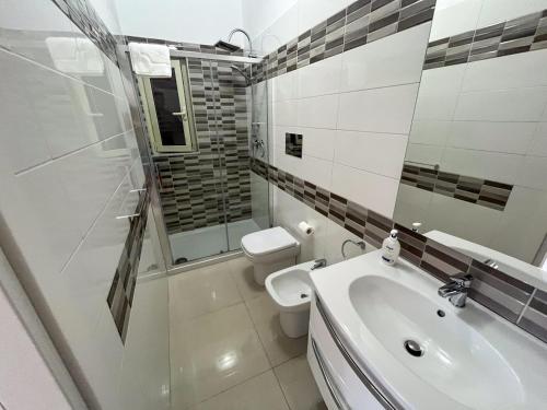 a white bathroom with a toilet and a sink at Suite Costa Sicana in Siculiana