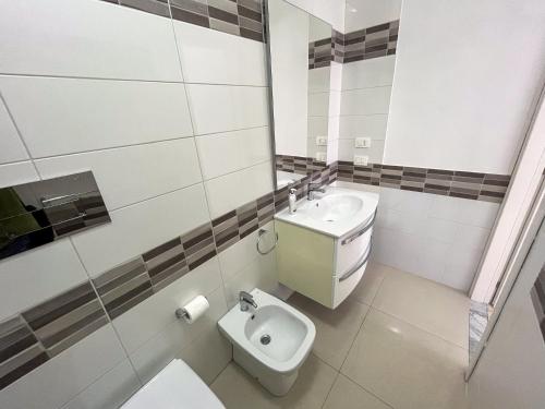 a white bathroom with a toilet and a sink at Suite Costa Sicana in Siculiana