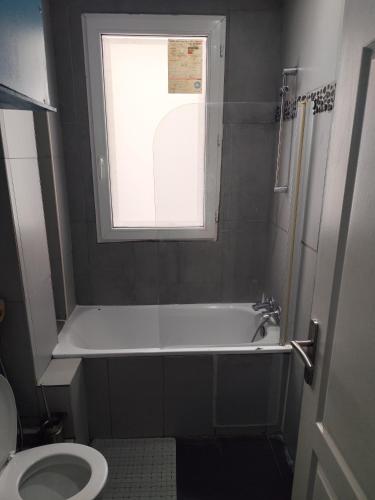 une salle de bain avec baignoire et toilettes et une fenêtre dans l'établissement F2 Au village St Denis, à Saint-Denis