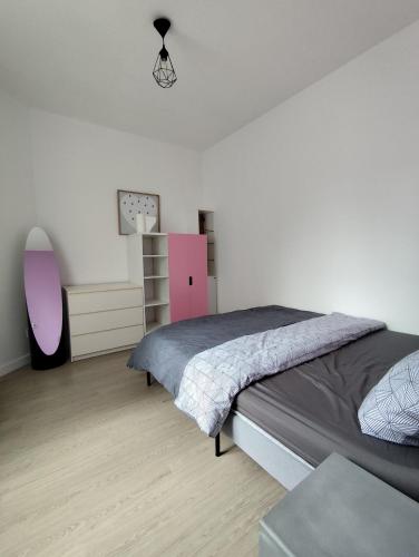 - une chambre avec un grand lit et une commode rose dans l'établissement F2 Au village St Denis, à Saint-Denis