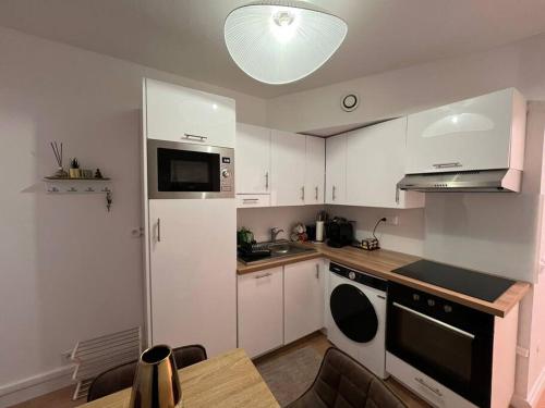 une petite cuisine avec des armoires blanches et une table dans l'établissement Residence 18 - Paris Rive Gauche, à Paris