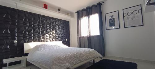 une chambre avec un lit avec un mur noir dans l'établissement Chez Delphine, à Théza