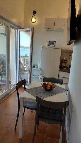a kitchen with a table with a bowl of fruit on it at Studio apartman Dolin in Rab