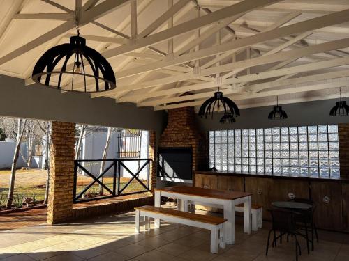 a room with a table and benches and windows at Bel-Air Guesthouse in Klerksdorp
