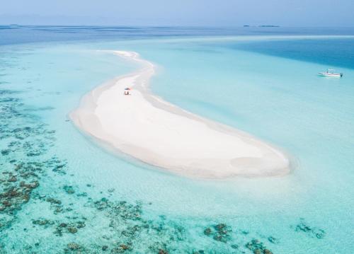 an island in the ocean with two people on it at Ostrov Beach in Ukulhas