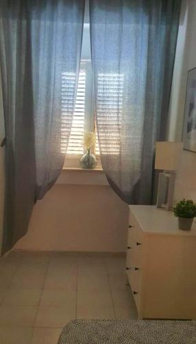 a room with a window with blue curtains and a desk at Pietra & Mare Ostuni in Villanova di Ostuni