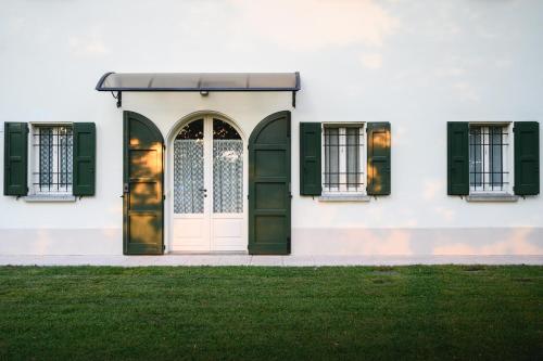 a white house with green shutters and a door at Casa Luisa in Lesignana