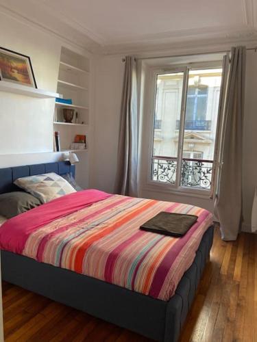 - une chambre avec un lit doté d'une couverture colorée et d'une fenêtre dans l'établissement Superbe appartement Paris 17ème 55m2, à Paris