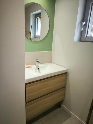 une salle de bain avec un lavabo et un miroir dans l'établissement La boite à coucou, Appartement pour 6 personnes, avec jardin , vue mer, à 400 m de la plage pors mabo, à Trébeurden