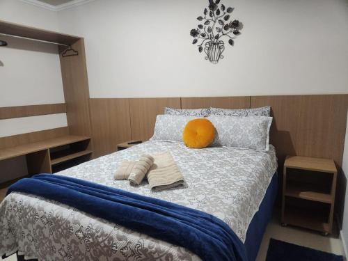 a bed with two towels and an orange ball on it at Inspire GuestHouse in Campos do Jordão