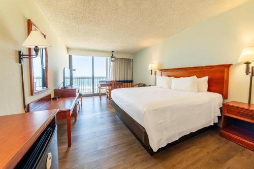 a hotel room with a bed and a balcony at The Oceanfront Inn - Virginia Beach in Virginia Beach