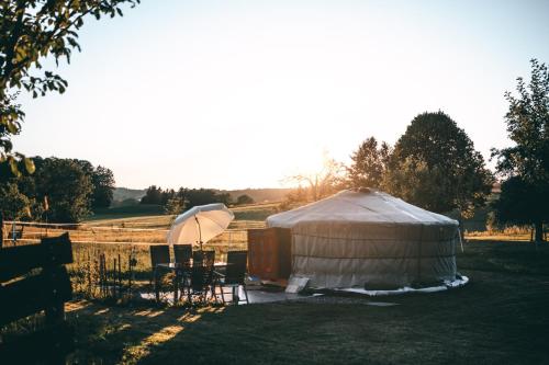 a yurt with chairs and an umbrella in a field at Hof Zürnens Oase in Wolfegg