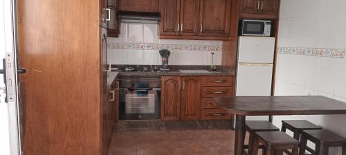 a kitchen with wooden cabinets and a table and a refrigerator at La Restinga Casa Mari in La Restinga