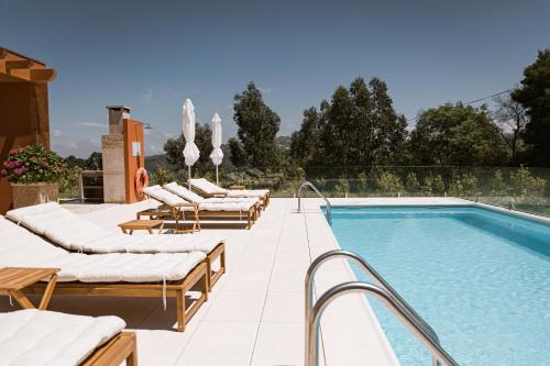 a row of lounge chairs next to a swimming pool at Souto Village - by RowdHouses in Maureles